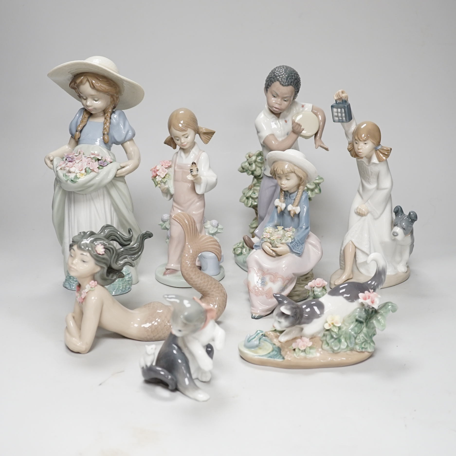 A large Lladro figure of a flower girl, mermaid, boy playing a drum and five other models including a Nao example, the largest 24cm high (8)